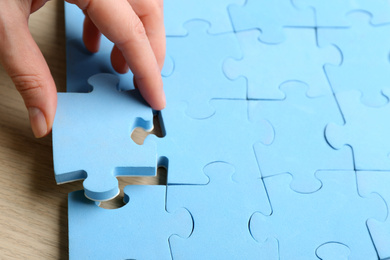 Photo of Woman putting light blue puzzle piece, closeup with space for text. Career promotion concept