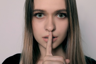 Photo of Abused woman making silent gesture on light background. Stop violence