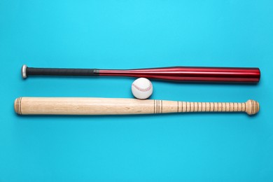 Photo of Baseball bats and ball on light blue background, flat lay
