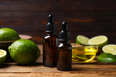 Photo of Lime essential oil and cut citrus fruits on wooden table