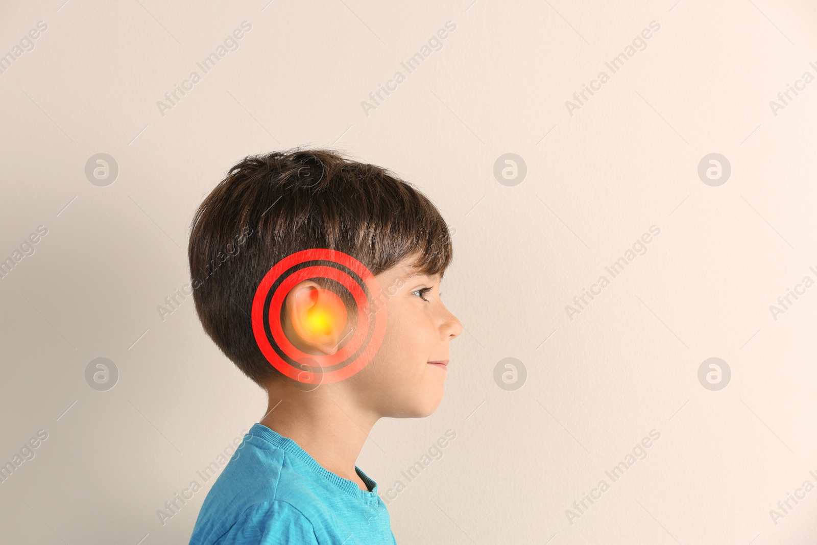 Image of Little boy on beige background. Hearing problem