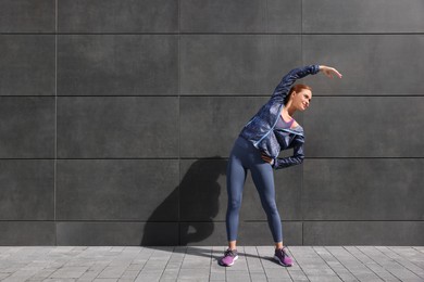 Photo of Beautiful woman in gym clothes doing exercises on street, space for text