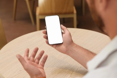 Photo of Man using smartphone at wooden table in cafe, closeup