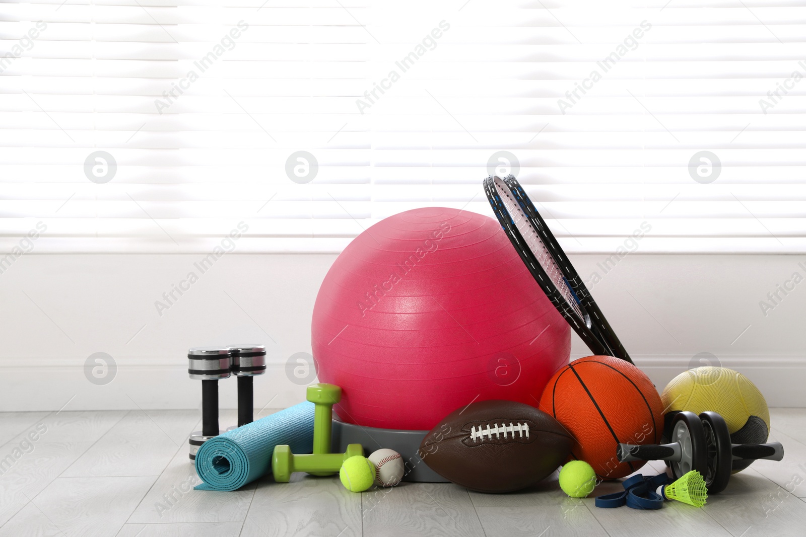 Photo of Set of different sports equipment on white floor indoors