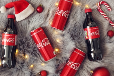 MYKOLAIV, UKRAINE - January 01, 2021: Flat lay composition with Coca-Cola drinks and Christmas decorations on fur background