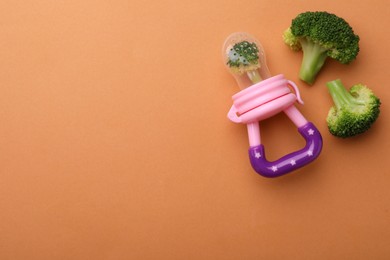 Photo of Nibbler with boiled broccoli on pale orange background, flat lay. Space for text
