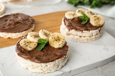 Photo of Puffed rice cakes with chocolate spread, banana and mint on board, closeup
