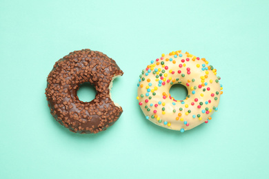 Delicious glazed donuts on turquoise background, flat lay