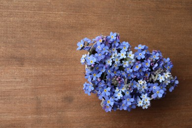 Heart of beautiful blue forget-me-not flowers on wooden table, top view. Space for text