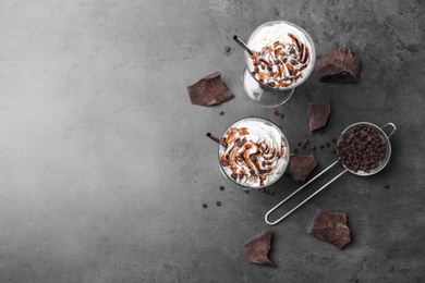 Glasses with chocolate milk shakes on grey table, top view