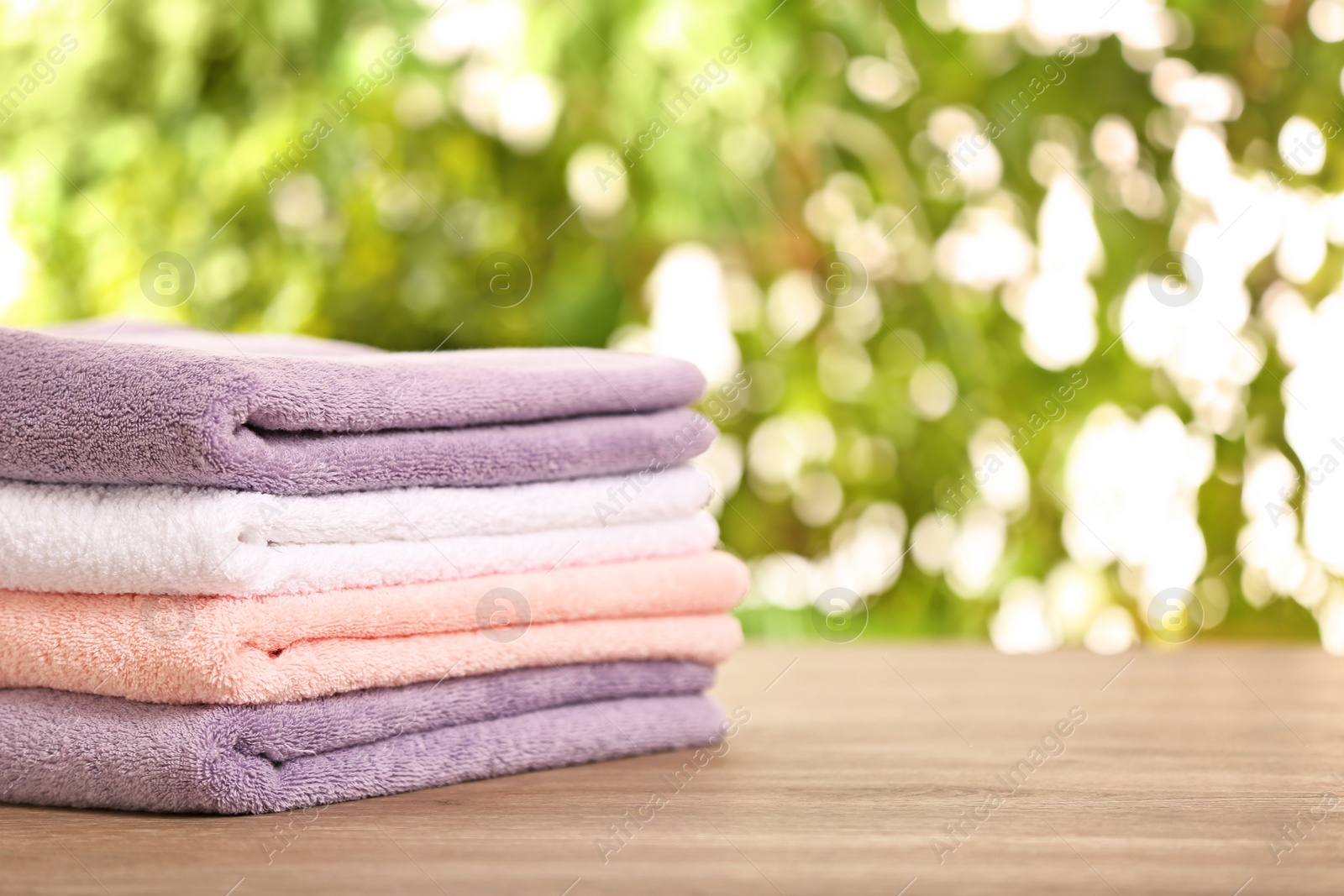 Photo of Stack of clean towels on table against blurred background. Space for text