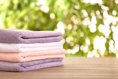 Stack of clean towels on table against blurred background. Space for text