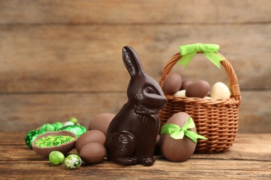 Photo of Dark chocolate Easter bunny and eggs on wooden table