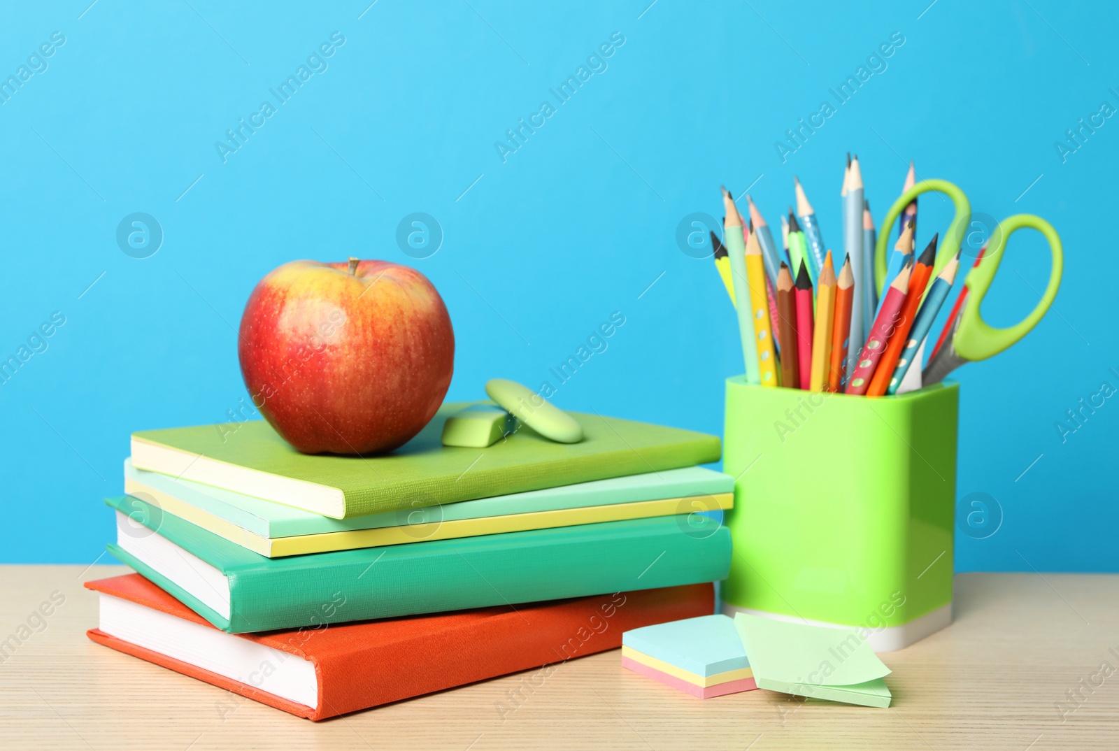 Photo of Composition with different school stationery on wooden table against light blue background. Back to school