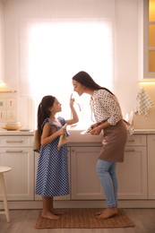 Mother and daughter wiping dishes together in kitchen