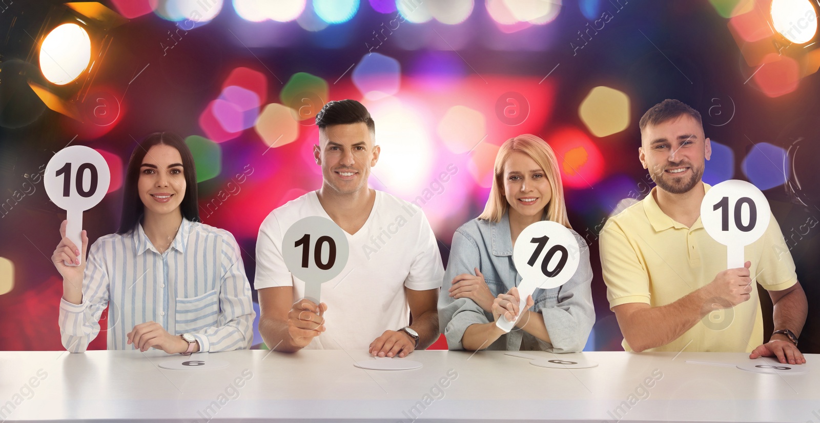 Image of Panel of judges holding signs with highest score at table against blurred background. Bokeh effect