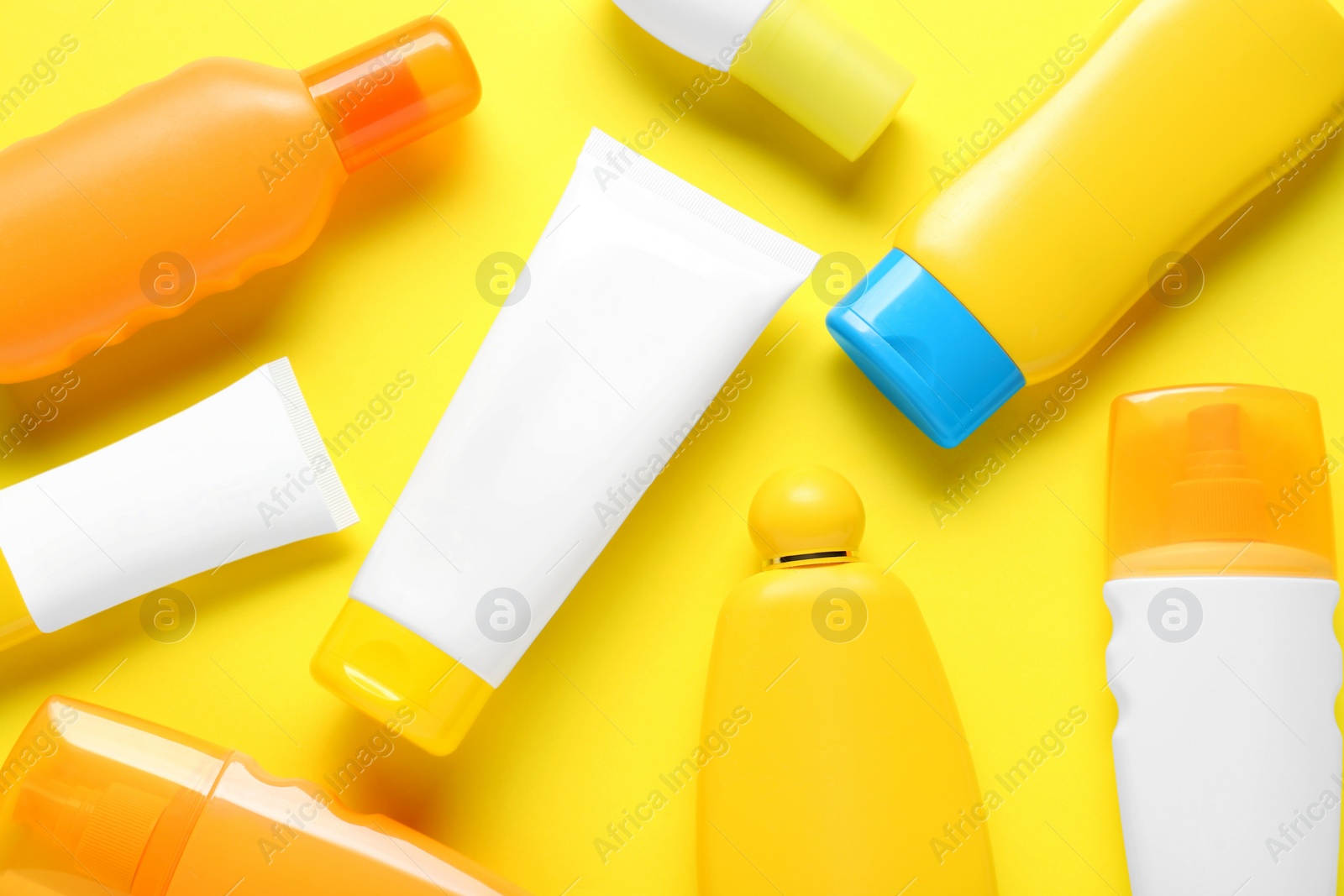 Photo of Suntan products on yellow background, flat lay