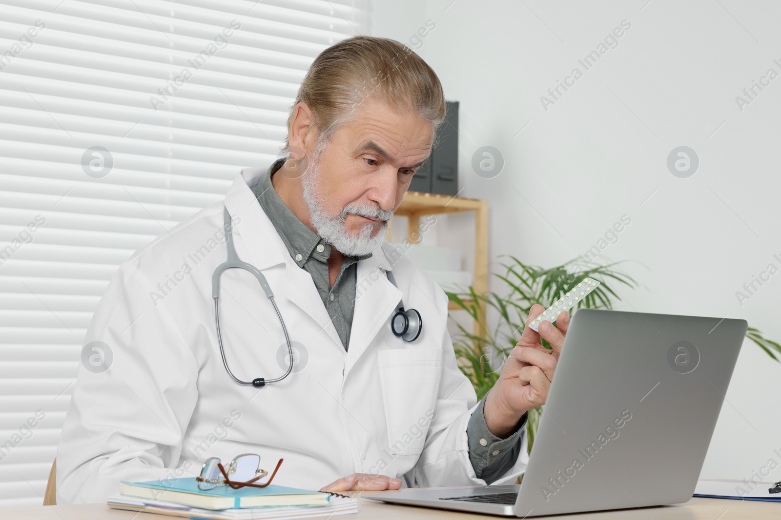 Photo of Senior doctor with laptop consulting patient at wooden desk in clinic. Online medicine