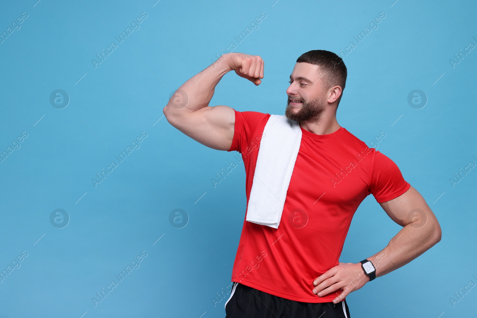 Photo of Handsome sportsman with white towel showing muscles on light blue background, space for text