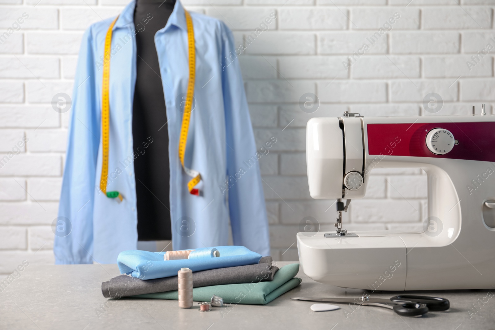 Photo of Sewing machine, fabrics and accessories for tailoring on table