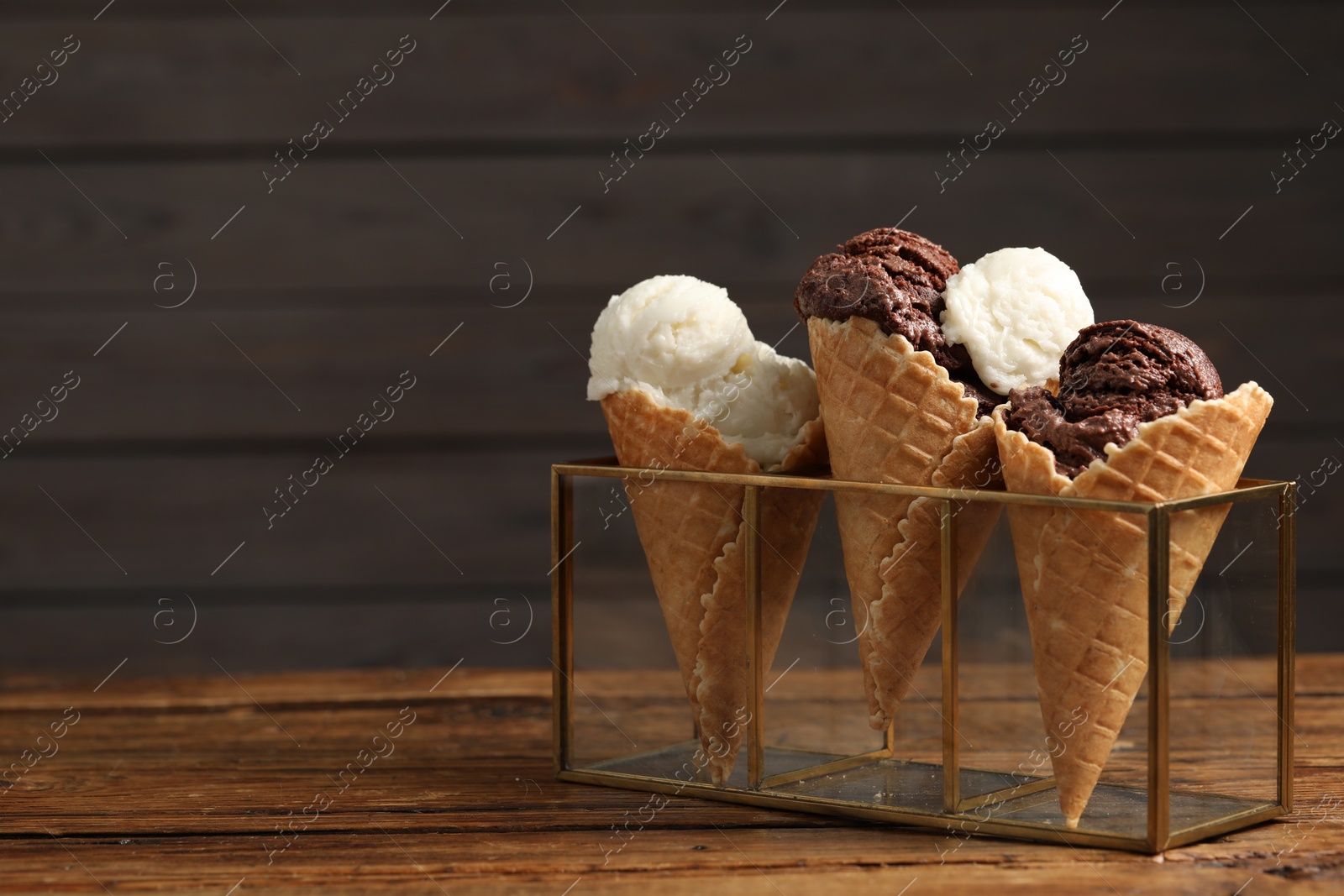 Photo of Tasty ice cream scoops in waffle cones on wooden table, closeup. Space for text