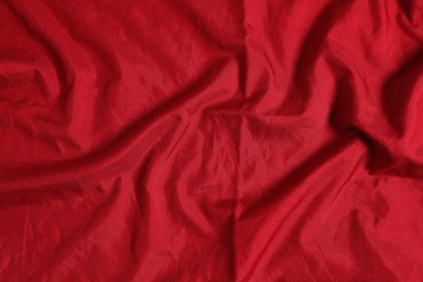 Crumpled dark red fabric as background, top view