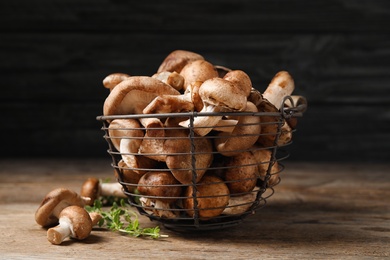 Different wild mushrooms in metal basket on wooden table
