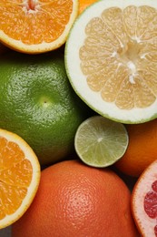 Different fresh whole and cut citrus fruits as background, top view