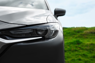 Photo of New black modern car outdoors, closeup of headlight