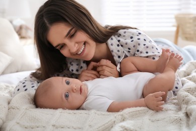 Mother with her cute baby on bed at home