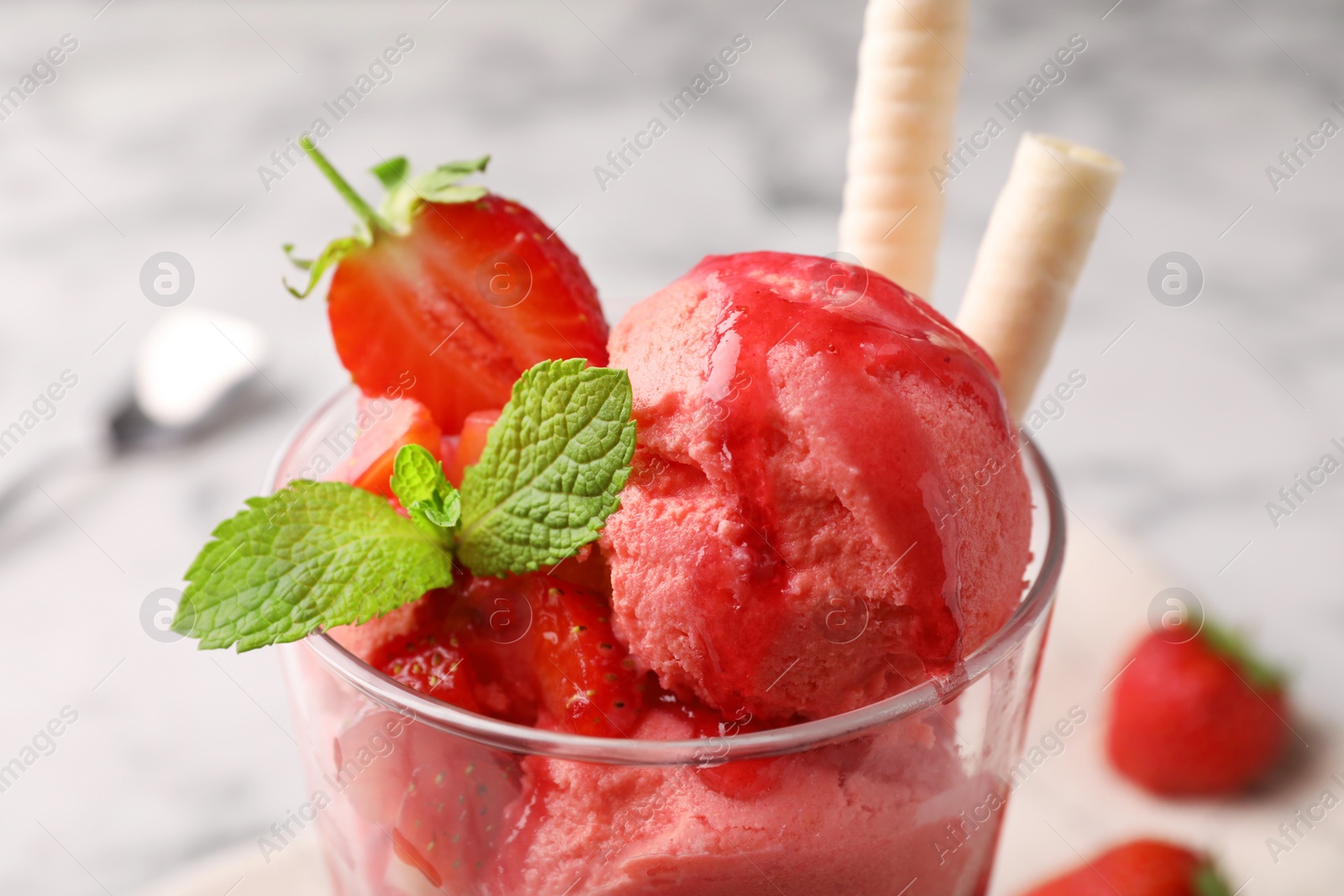 Photo of Tasty strawberry ice cream with fresh berries and wafer rolls in glass dessert bowl on table, closeup