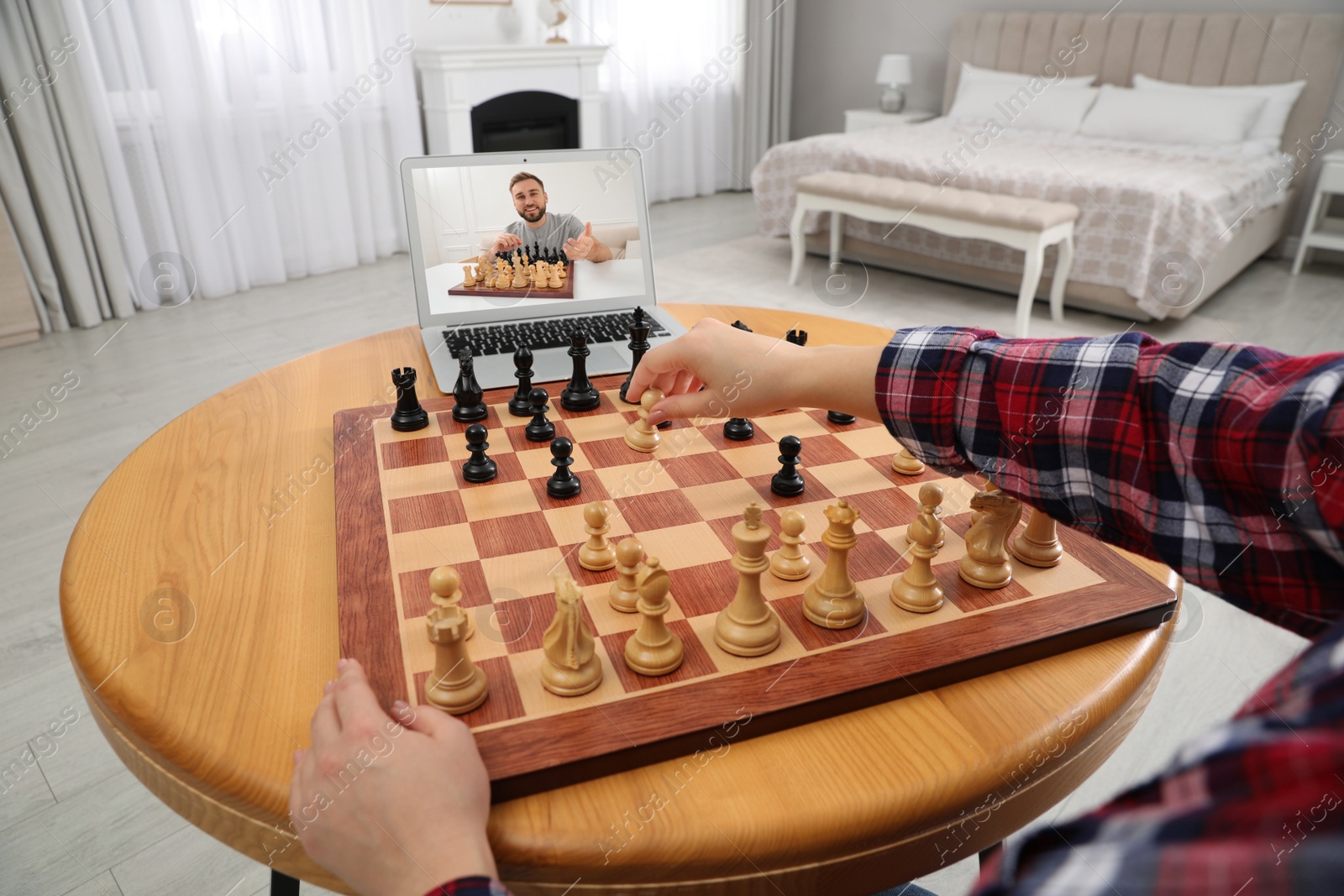Image of Woman playing chess with partner via online video chat at table indoors, closeup