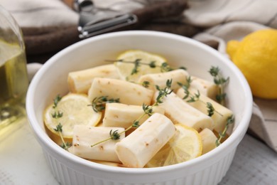 Photo of Dish with raw salsify roots, lemon and thyme on table, closeup