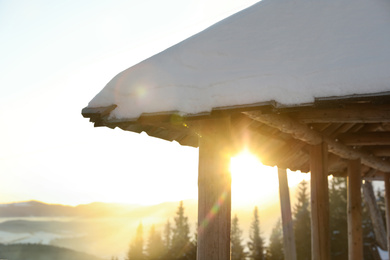 Photo of Wooden gazebo near snowy coniferous forest, closeup. Winter vacation