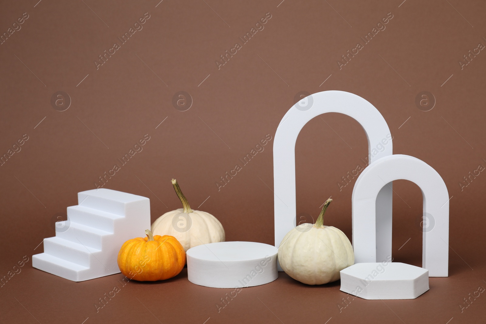 Photo of Autumn presentation for product. White geometric figures and pumpkins on brown background