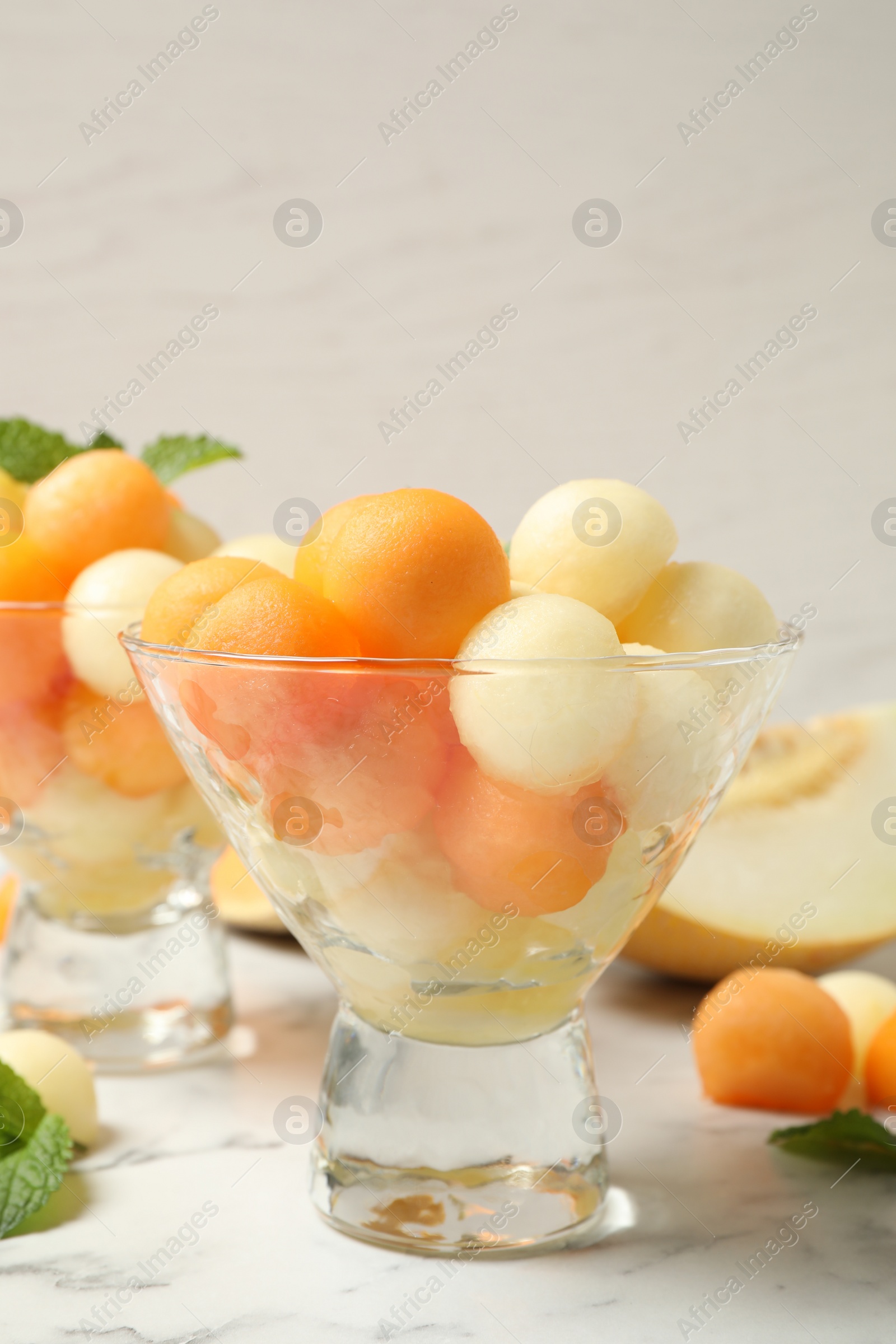 Photo of Melon balls and mint on white marble table, closeup