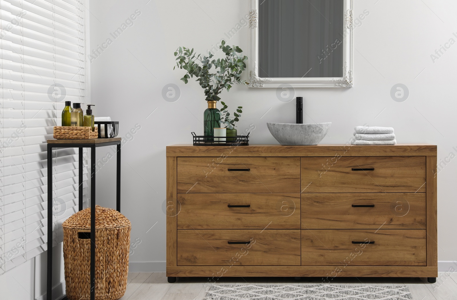 Photo of Modern bathroom interior with stylish mirror, eucalyptus branches, vessel sink and wooden vanity