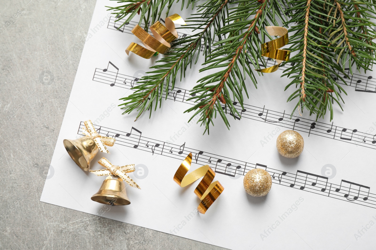Photo of Christmas decorations and music sheet on grey stone table, flat lay