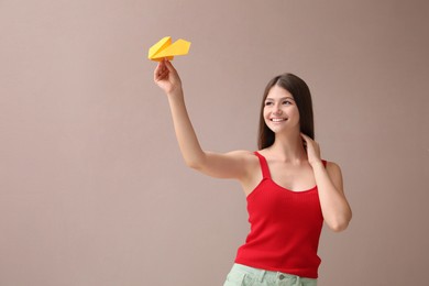 Photo of Beautiful teenage girl with paper plane on beige background. Space for text