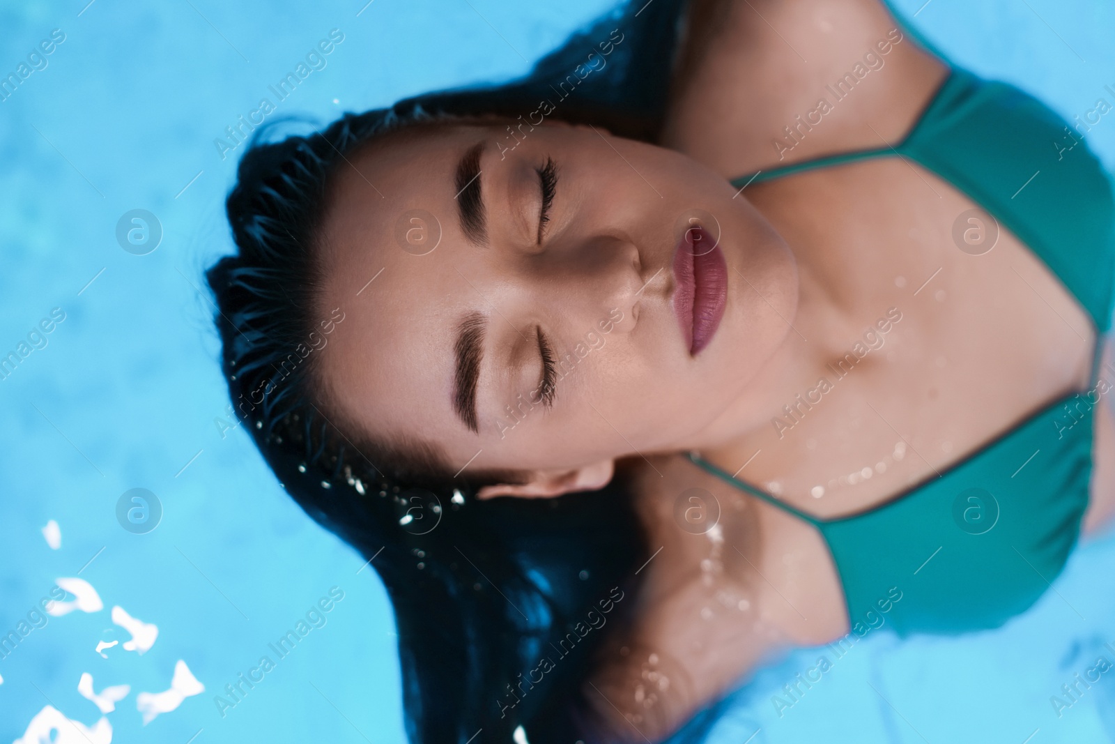 Photo of Beautiful woman relaxing in spa swimming pool, top view