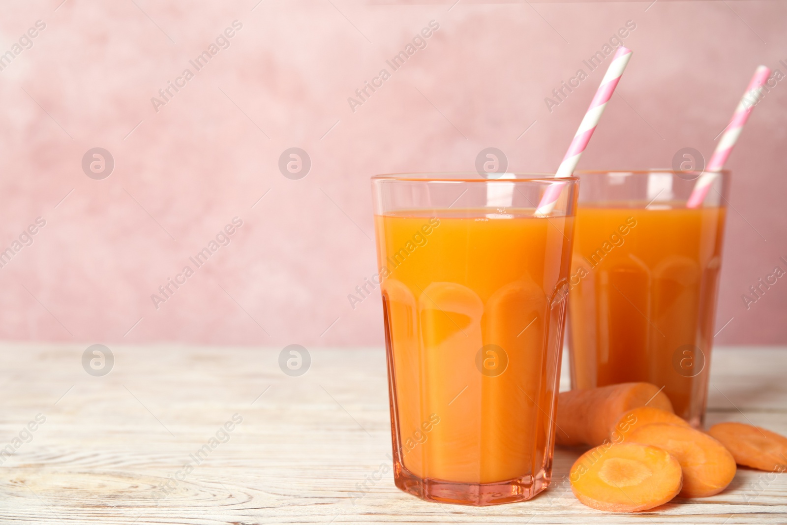 Photo of Freshly made carrot juice on wooden table. Space for text