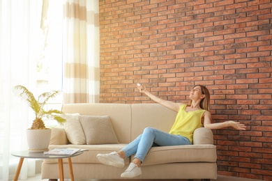 Happy woman with air conditioner remote at home