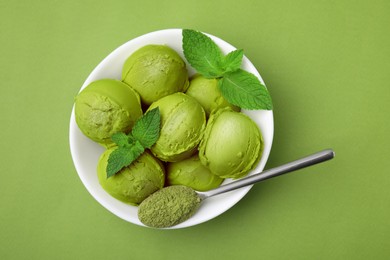 Photo of Tasty matcha ice cream and spoon with powder in bowl on green table, top view