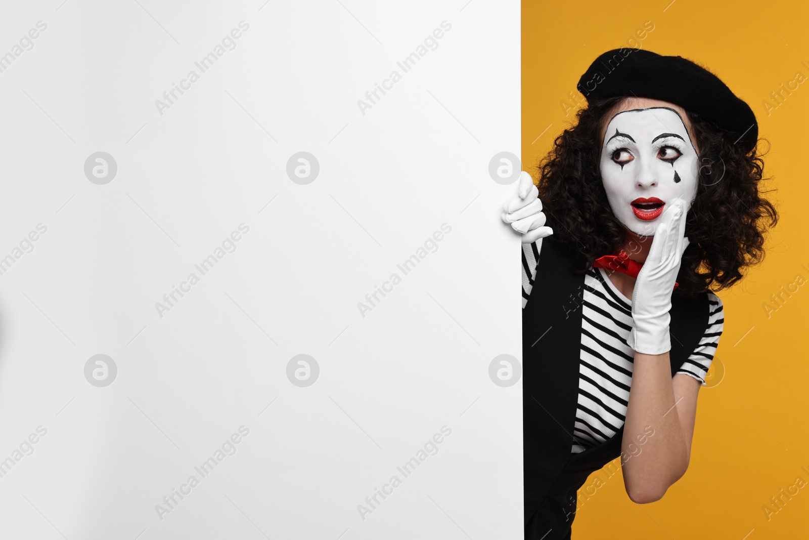 Photo of Funny mine with blank poster posing on orange background, space for text