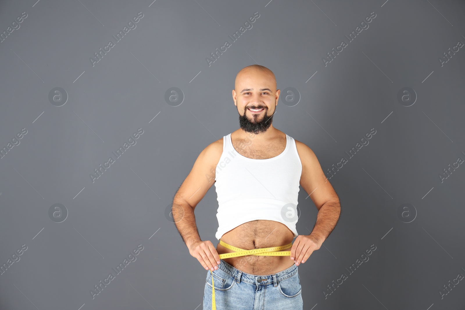 Photo of Overweight man with measuring tape on gray background