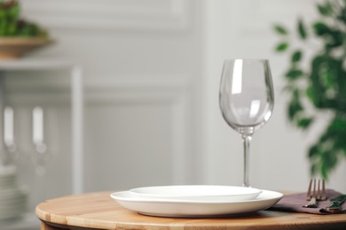 White plates and wineglass served for dinner on wooden table