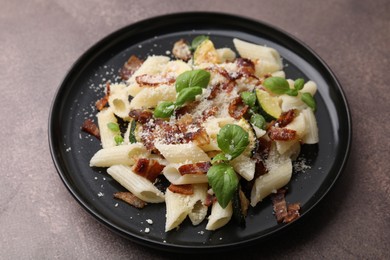 Tasty pasta with bacon and basil on brown table