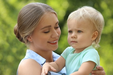 Young mother with her cute child in green park