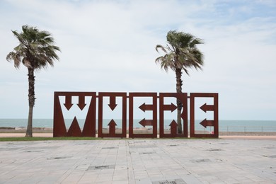 Batumi, Georgia - June 24, 2022: Beautiful art installation with word WHERE and palm trees near sea