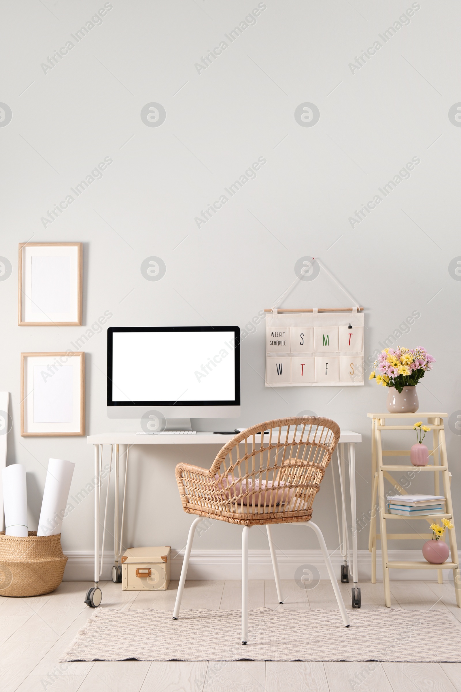 Photo of Comfortable workplace with modern computer and flowers in room. Interior design